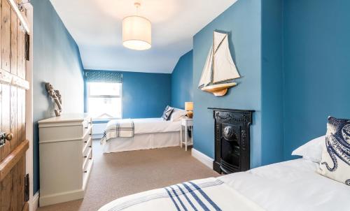 a blue bedroom with two beds and a sailboat on the wall at Lobster Cottage Lytham in Lytham St Annes