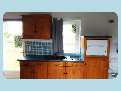 a kitchen with wooden cabinets and a sink and a window at La Ferme du Parc in Pendé