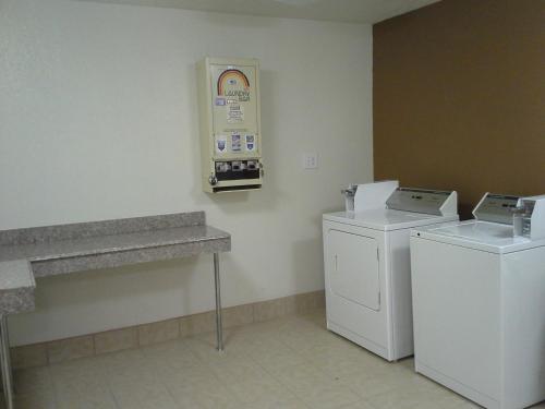 a laundry room with two machines and a sign on the wall at Sky Tree Hotels in Tulsa