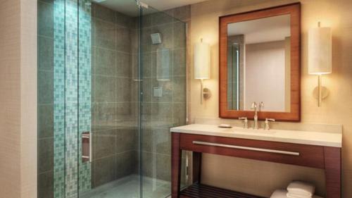 ein Bad mit einer Dusche, einem Waschbecken und einem Spiegel in der Unterkunft Seven Clans Hotel at Coushatta in Kinder