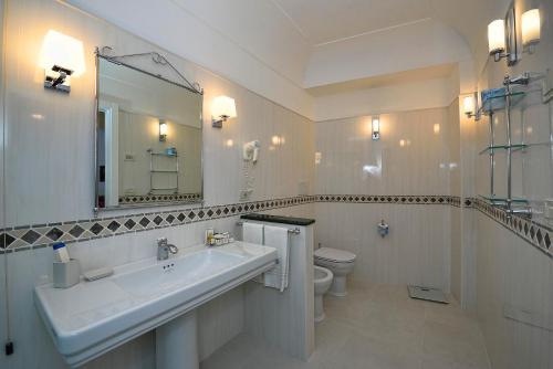 a bathroom with a sink and a toilet and a mirror at Hotel Belvedere in Conca dei Marini