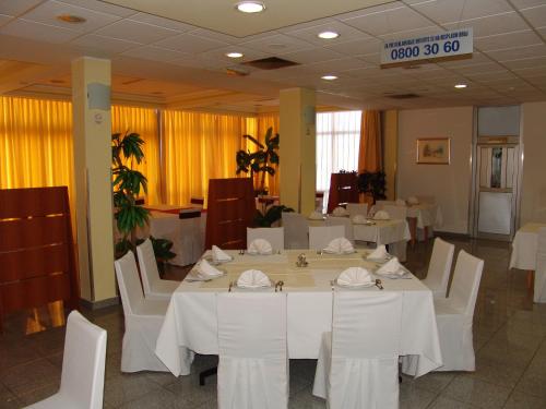 a dining room with white tables and white chairs at Hotel Zovko in Slavonski Brod