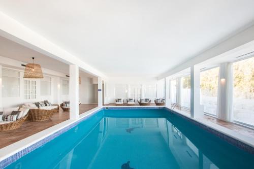 a swimming pool in a house with a room with windows at Casa Victoria Suites in Sant Josep de sa Talaia