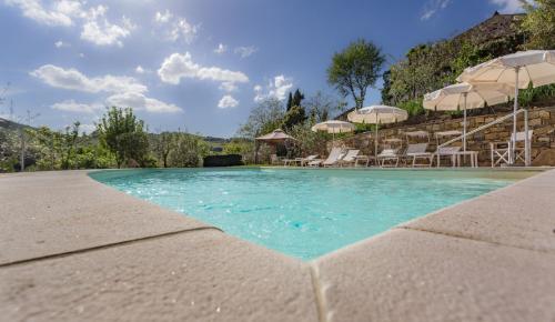 a swimming pool with chairs and umbrellas in a resort at Casale Le Masse in Greve in Chianti