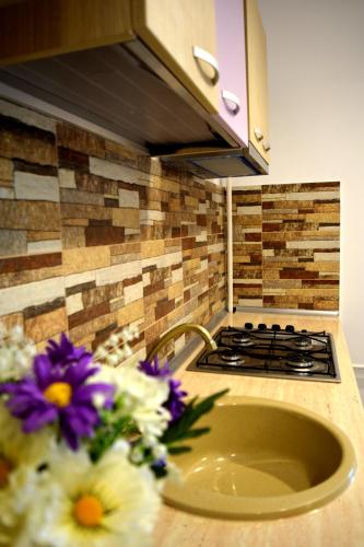 a kitchen with a sink and a stove and some flowers at Apartament Liliac in Bucharest