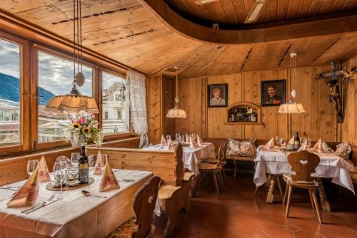 restauracja ze stołami i krzesłami w pokoju z drewnianymi ścianami w obiekcie Furggerhof w mieście Tirolo