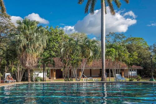 a swimming pool in front of a house with palm trees at Hotel Hacienda La Pacifica in Cañas