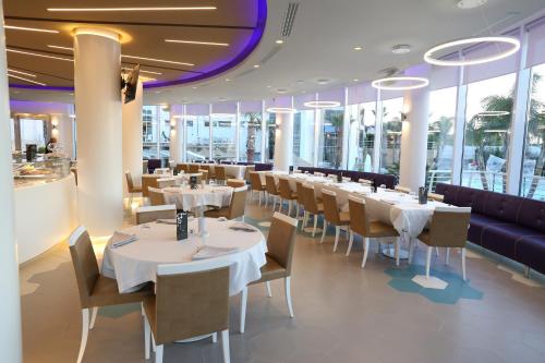 a restaurant with white tables and chairs and windows at DubaiVillage in Camposano