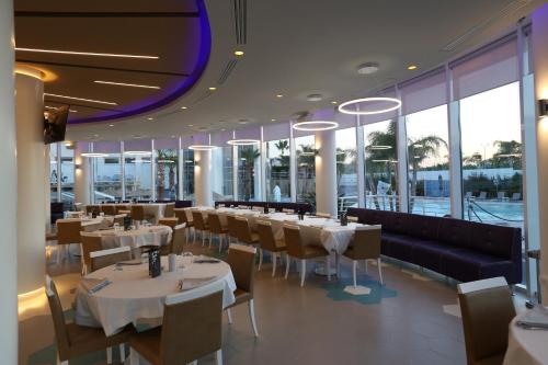 un ristorante con tavoli e sedie bianchi e finestre di DubaiVillage a Camposano