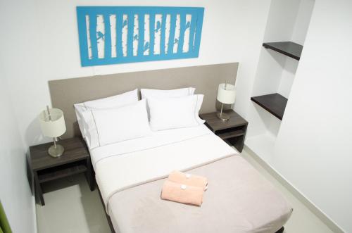 a small bedroom with a white bed and two tables at Hotel las Olas Malambo in Malambo