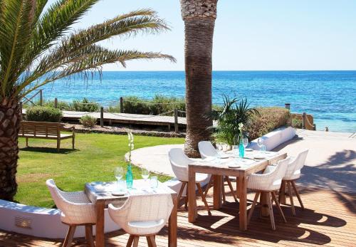 a table and chairs with the ocean in the background at Gecko Hotel & Beach Club in Playa Migjorn