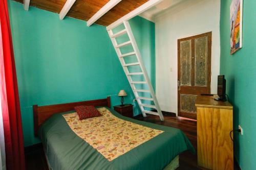 1 dormitorio con cama y escalera en la pared en Hostal Casa Verde Limón en Valparaíso