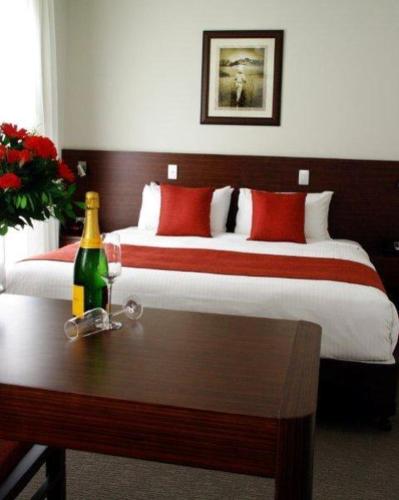 1 dormitorio con 1 cama y 1 botella de vino en la mesa en Mary River Motor Inn en Gympie