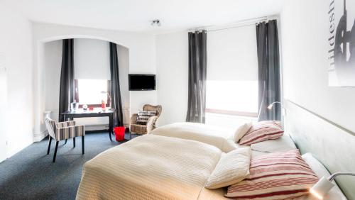 a bedroom with a bed and a desk and windows at 1891 Hildesheim Boutique Hotel in Hildesheim