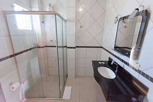 a bathroom with a glass shower and a sink at Nioja Hotel in Itumbiara