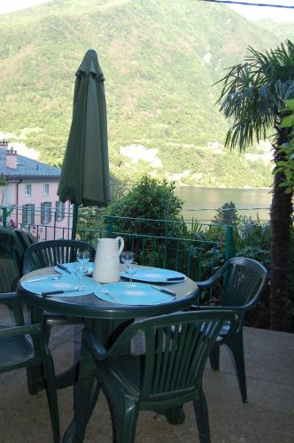 a table with a green umbrella and two chairs at Hotel Bersagliere in Laglio