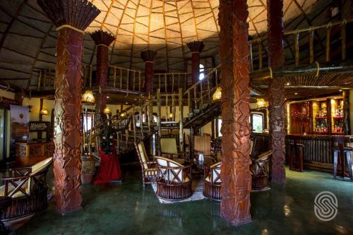 a bar with wooden columns and chairs in a room at Serengeti Serena Safari Lodge in Serengeti National Park