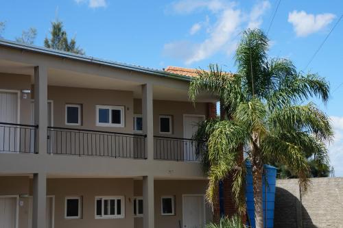 a building with a palm tree in front of it at Coimbra Hotel Pousada in Pelotas