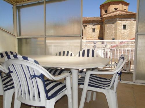 a white table and chairs with a tower in the background at Cal Marsal in Aitona