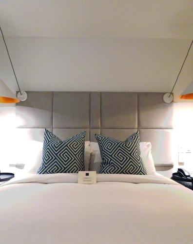 a bedroom with a bed with blue and white pillows at C3- Hotel Art De Vivre in Quebec City