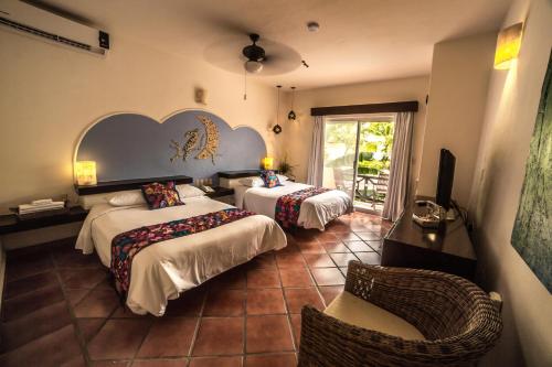 a hotel room with two beds and a chair at Hotel Riviera Del Sol in Playa del Carmen