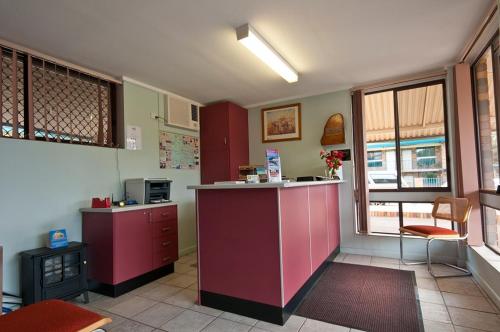 a kitchen with a refrigerator, stove, sink and a window at Fig Tree Motel in Narrandera