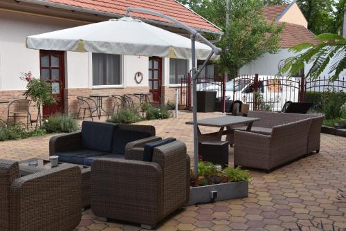 a patio with wicker furniture and a table and an umbrella at Guest House Romantika Panzio in Gyula