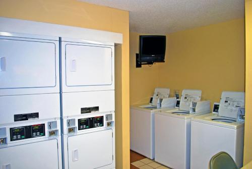 a laundry room with washers and dryers and a tv at Extended Stay America Select Suites - St Louis - Airport - Central in Bridgeton