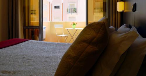 a bed with pillows in a room with a window at Hotel Apolo in Vila Real de Santo António