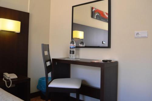 a room with a vanity with a chair and a mirror at Hotel Apolo in Vila Real de Santo António