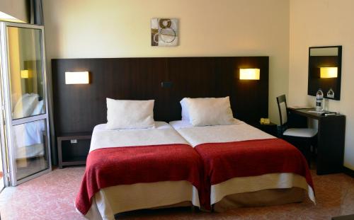 a bedroom with a large bed with a red and white blanket at Hotel Apolo in Vila Real de Santo António