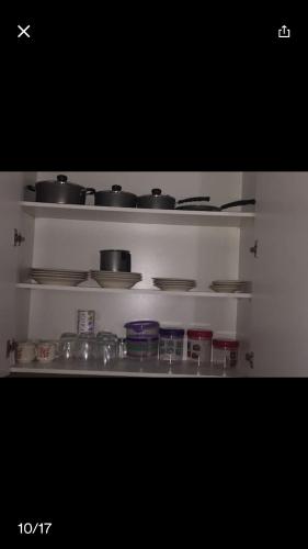 a white shelf with pots and pans on it at Apartamento confortável in Goiânia