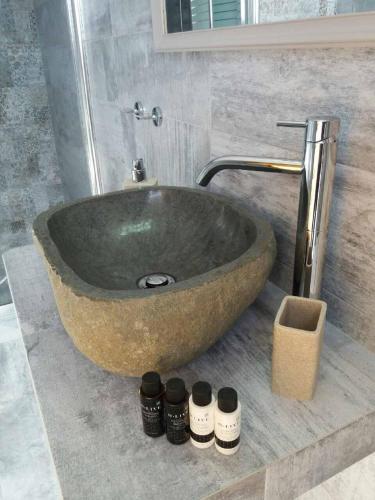 a large stone sink in a bathroom with four bottles at Drougas' Windmill in Plaka Milou
