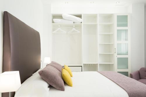 a bedroom with a white bed with yellow pillows at AiA EXCLUSIVE APARTMENTS in Granada