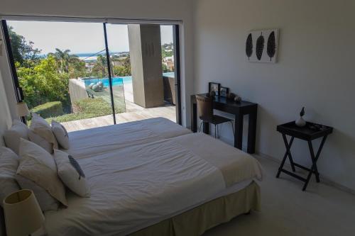 a bedroom with a bed and a sliding glass door at Evane in Plettenberg Bay