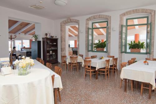 a dining room with white tables and chairs and mirrors at Hotel Televrin in Nerezine