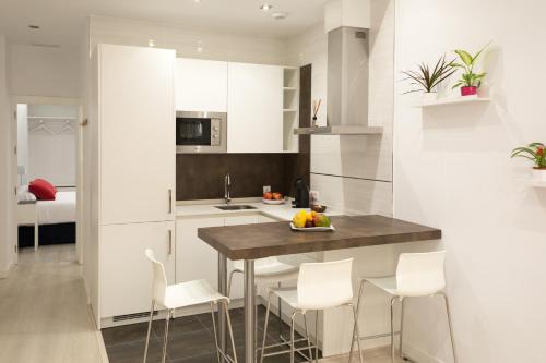 a kitchen with white cabinets and a table and chairs at AiA EXCLUSIVE APARTMENTS in Granada