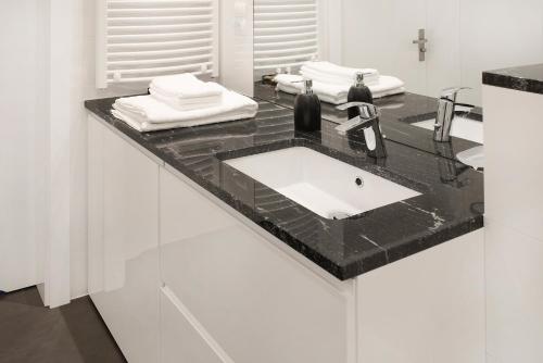 a white bathroom with a black counter and a sink at Art Room Boutique Apartment in Krakow