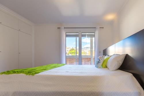 een witte slaapkamer met een groot bed en een raam bij Casa dos Avós by Rent2U, Lda in Funchal
