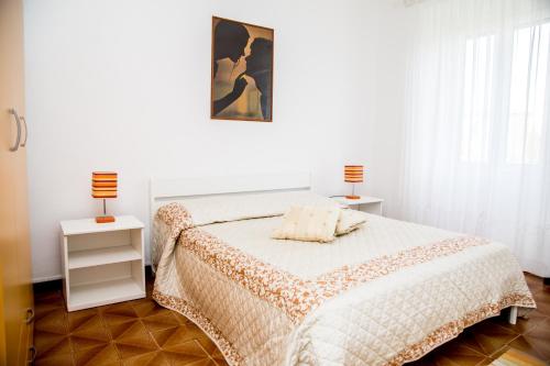 a white bedroom with a bed and two lamps at Casa Fertilia in Fertilia
