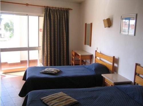 a hotel room with two beds and a balcony at Apartamentos Turisticos Silchoro in Albufeira