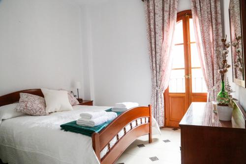 a bedroom with a bed with a table and a window at Casa Las Nieves in Arcos de la Frontera