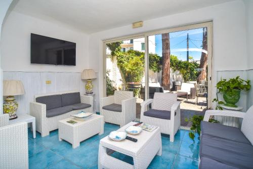 a living room with white furniture and a patio at Charme Hotel La Villa Tina in Ischia