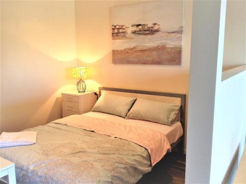 a bedroom with a bed and a painting on the wall at Glen Waverley Apartment in Glen Waverley