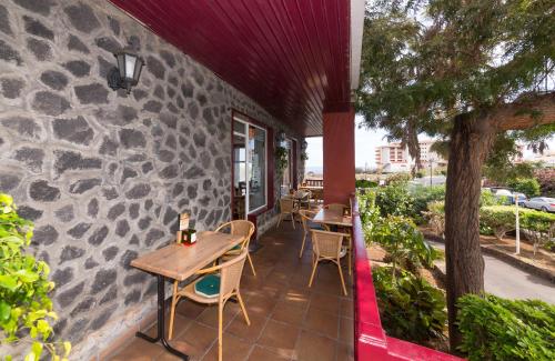 a patio with tables and chairs and a stone wall at Apartamentos Centro Cancajos in Los Cancajos