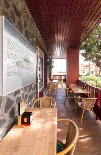 a restaurant with wooden tables and chairs and a large screen at Apartamentos Centro Cancajos in Los Cancajos