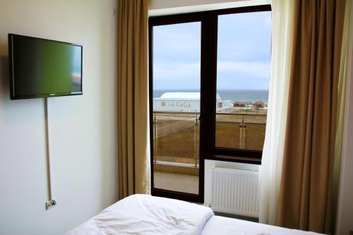a room with a bed and a window with a television at Holiday Summerland Apartment in Mamaia