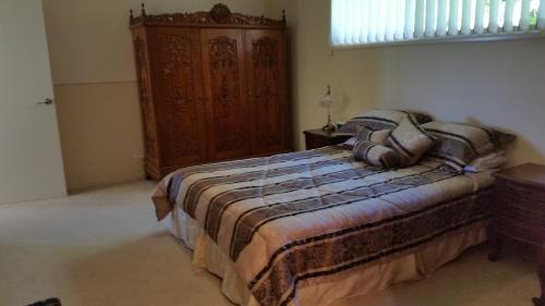 a bedroom with a bed and a wooden cabinet at Hilltop Hideaway in Ninderry