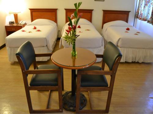 a hotel room with two beds and a table and chairs at West Plaza Malakal in Koror