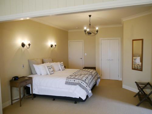 a bedroom with a large white bed and a mirror at Country Lodge Kinloch in Taupo